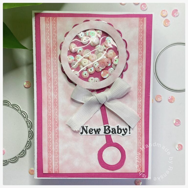 My finished baby rattle card with lots of pink on the digital design paper and a rattle shaker on top.