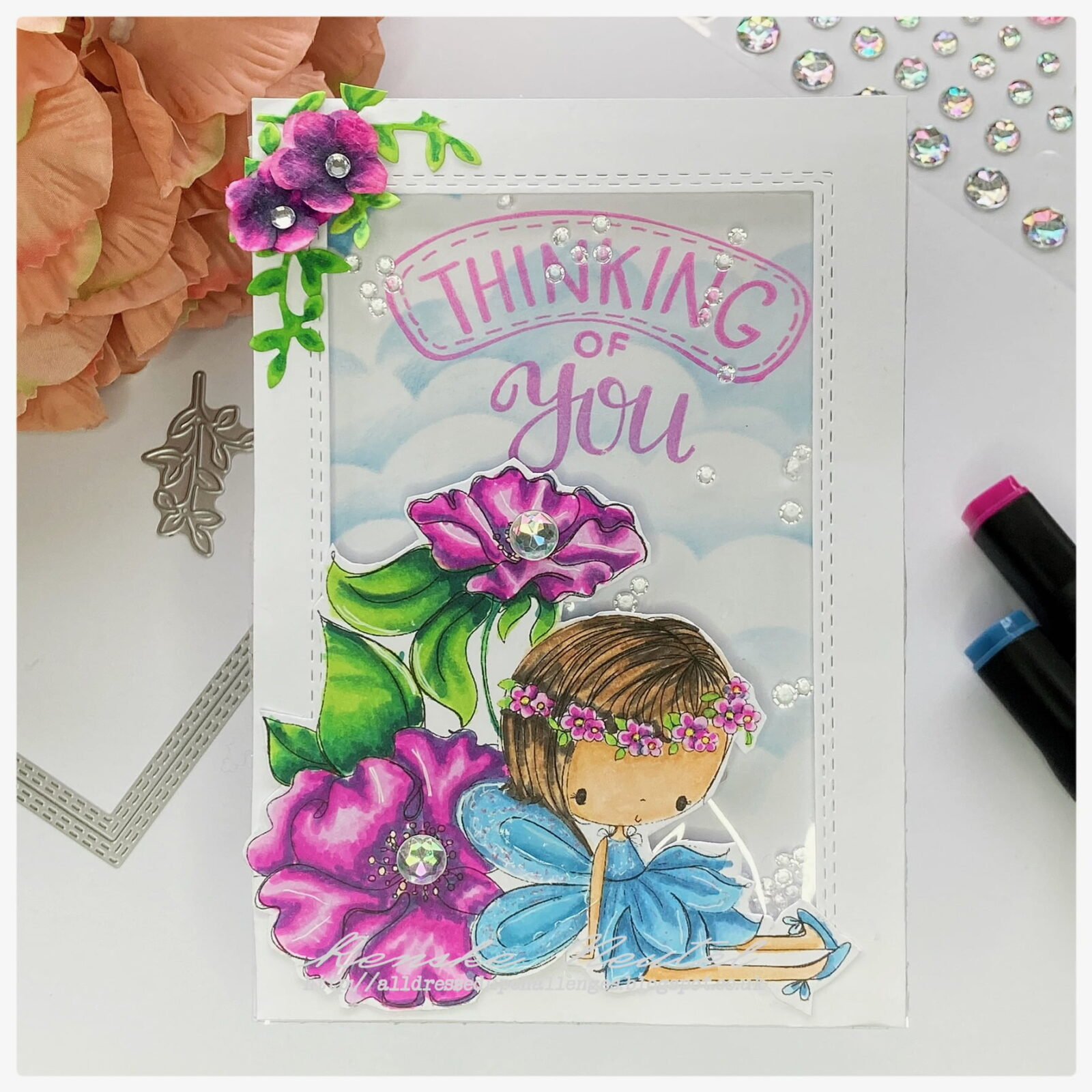 Picture of the finished little flower fairy shaker card. The fairy is sitting against two purple flowers. Her dress is blue.