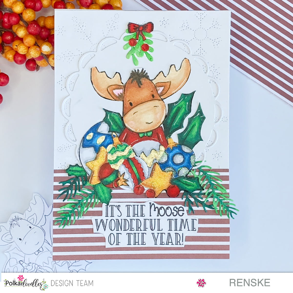 Festive Christmas in July card featuring Polkadoodles' Elvis Wesley Moose. Handcrafted with love and colored using alcohol markers. The moose is surrounded by holly, ornaments, and stars on a charming patterned background. Joyful and magical holiday vibes captured in this handmade creation.