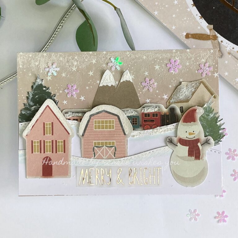 Featured image of a beautifully crafted DIY Christmas card with festive decorations and a heartfelt message. It's a Christmas village with snow.