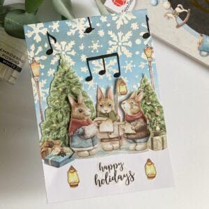 Festive Bunny Christmas Card displayed diagonally, featuring cute rabbits, holiday decorations, and a touch of shimmer.