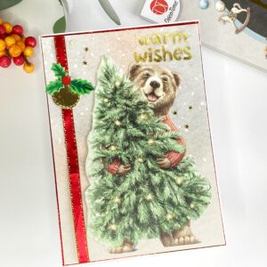 Image of creatively designed holiday card: Capturing a tilted angle to showcase a cheerful bear, a Christmas tree, and festive embellishments, adding a whimsical touch to the handmade card.