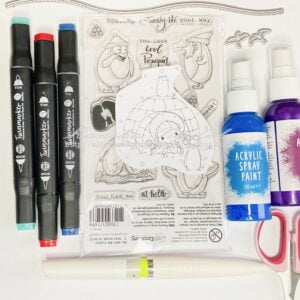 Image displaying various crafting materials utilized in creating the winter-themed card, including alcohol markers, embossing powder, clear stamps, and the Penguin Fun digital stamp.