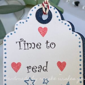 Detailed view of the handmade bookmark's top, featuring the prominent text "Time to Read" surrounded by carefully stamped red hearts, adding a delightful touch to the design.