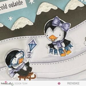 Close-up of Waddy,sledding across a snowy landscape on a winter-themed slimline slider card featuring Polkadoodles' penguins