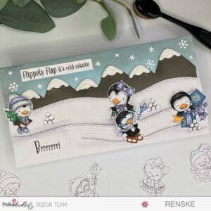Full view of a winter-themed slimline slider card, showcasing Polkadoodles' penguins, with Waddy's sled positioned in the middle of the sliding track.