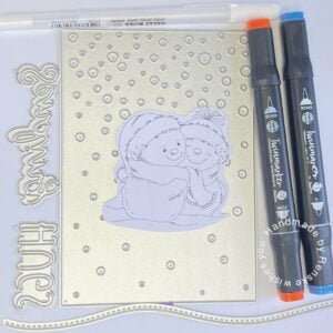 Picture of the materials use for this snowman sending hugs card. The sentiment dies, background dies, digital stamp, snow hill die and alcohol markers.