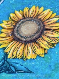 Close up picture layers sunflowers lose-up view of the layered sunflower centerpiece on a handmade mixed-media floral card, showcasing the intricate cutouts and stacked arrangement. The three-dimensional effect adds depth and visual interest to the card's design.