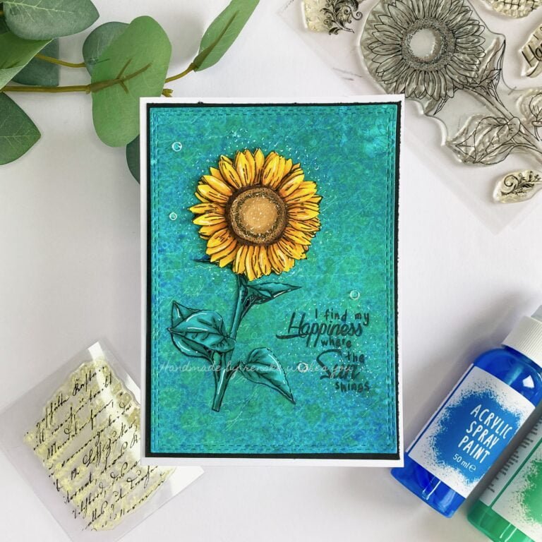Handcrafted mixed media flower card featuring a vibrant sunflower design on a textured background. The card is displayed from a top-down perspective, showcasing its intricate details and colourful composition.