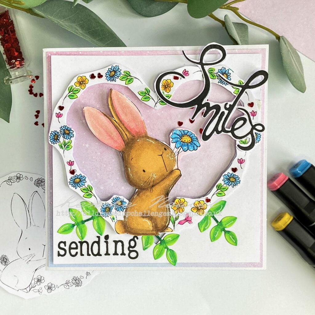 A top-down view of the "Say it with Flowers" card, showcasing the complete design. The card features a heart-shaped window with a charming scene of flowers and a rabbit holding a flower, surrounded by leafy foliage.