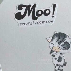 close up picture of the sentiment and cow on the inside of the card lose-up of greeting text and cow illustration inside the cow greeting card. The text 'Moo! means hello in cow' is prominently featured alongside a friendly cow extending a paw in greeting. The background is primarily white with black text, and the cow is depicted in shades of grey.