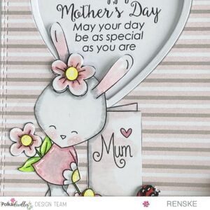 Close up picuture coloured digital stamp Bunny Rabbit Mum greeting card Polkadoodles Close-up of a colored digital stamp featuring an adorable bunny rabbit surrounded by flowers, holding a blank greeting card. The bunny is shaded in warm grey tones with blush pink accents on its dress and ears. The flowers are colored in shades of pink, yellow, and green, with intricate detailing.