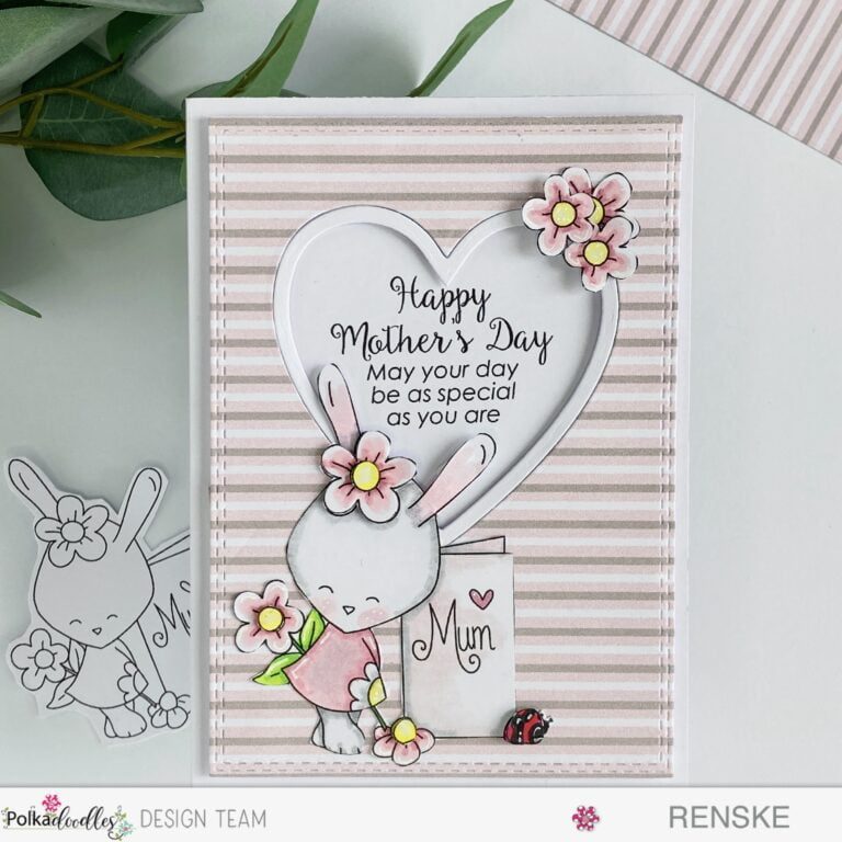 Handmade Mother's Day card featuring a bunny holding a blank greeting card surrounded by flowers. The card is placed flat on a surface, captured from a top-down perspective, showcasing the entire design.