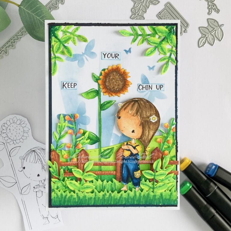 A top-down view of the entire handmade sunflower card, featuring a charming girl surrounded by vibrant sunflowers and greenery. The background showcases layered stencils with sun rays and butterflies, adding depth to the scene. This image provides an overview of the handmade sunflower card tutorial.