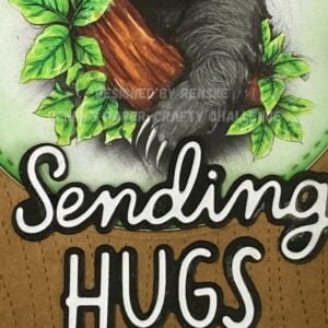 A close-up photo of the sentiment "sending hugs" on the handmade sloth card. The words "sending hugs" are elegantly displayed, adding a heartfelt message to the adorable sloth-themed