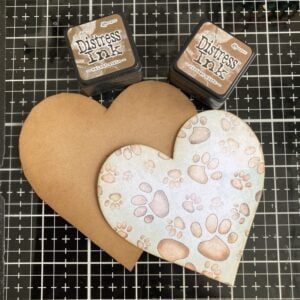Use distress ink to ink the edges of the hearts a heart shaped craft paper with a dog paw print and two colours of distress ink.