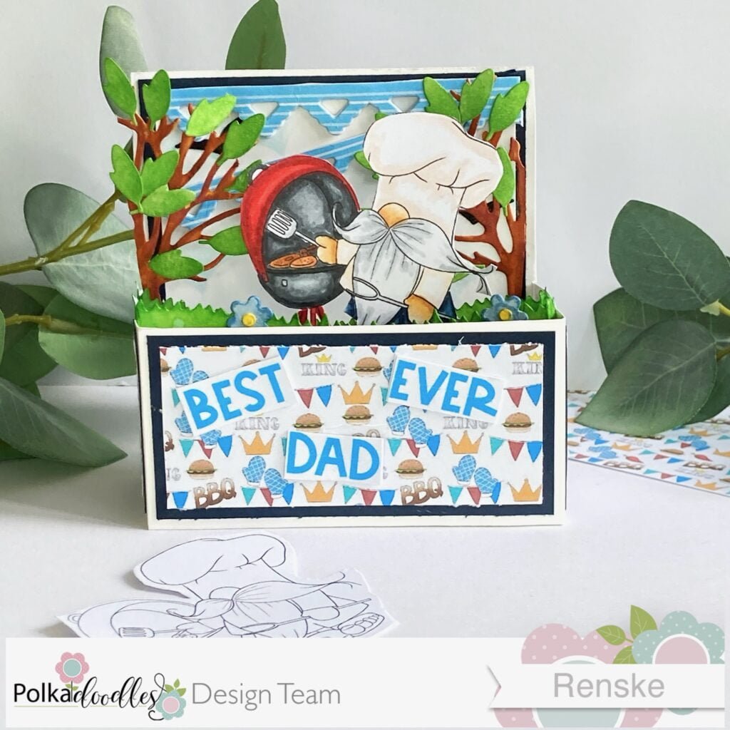Front view of Handmade Father's Day Card in a Box, showcasing the vibrant scene inside, featuring a charming gnome-themed BBQ party with colorful decorations, a barbecue grill, and festive banners.