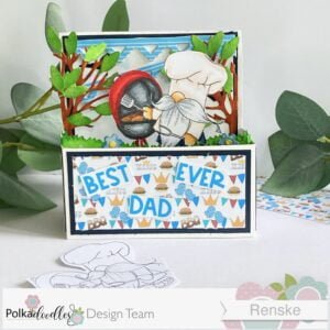 Father's Day card in a box Polkadoodles 1 Front view of Handmade Father's Day Card in a Box, showcasing the vibrant scene inside, featuring a charming gnome-themed BBQ party with colorful decorations, a barbecue grill, and festive banners.