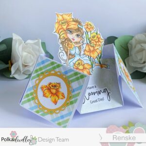 Flower card in unuasal shape with Daffodil flower girl Polkadoodles (2) Angled view of the completed double-diamond card with the left side facing the camera, highlighting its dimensional structure with the daffodil flower girl in blue, white and yellow flowers.