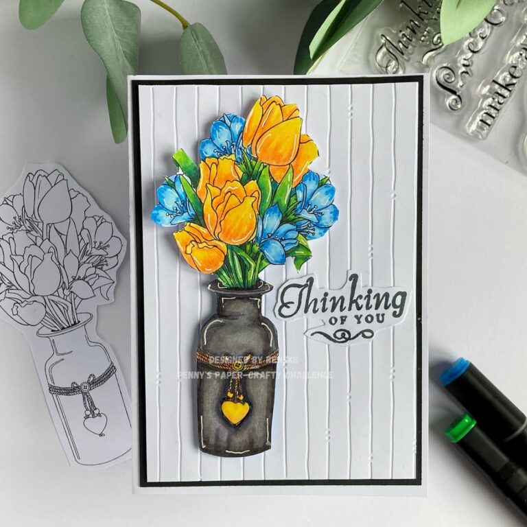 Top view of a handmade floral card, showcasing vibrant colored yellow and blue flowers in a black vase, flat and straight in the frame.