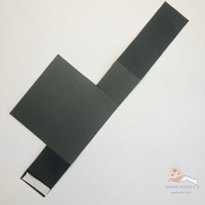 Taped base of the card in a box Black card base for a Halloween card in a box with double-sided tape applied, indicating where to place the tape for assembly.