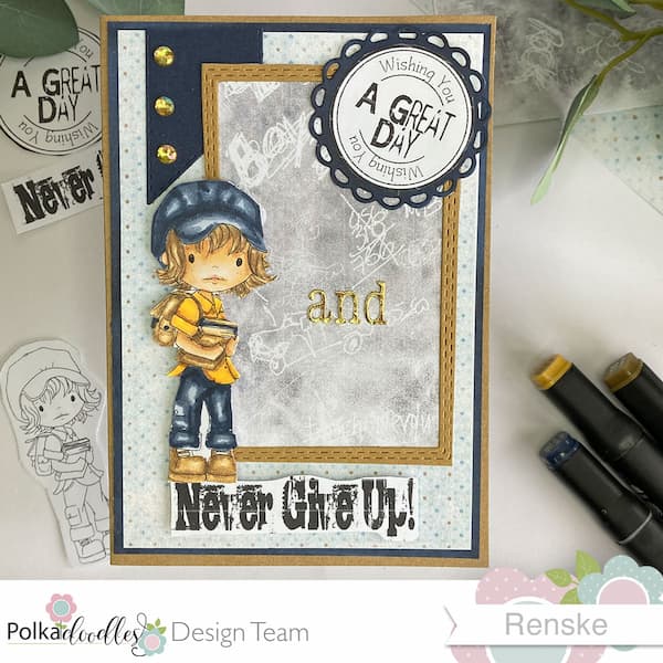 Flat lay of the finished handmade back-to-school card viewed from directly above. The card features a kraft base with a blue and pattern paper layer. A rectangular kraft frame with a chalkboard pattern paper is centered on the card. Inside the frame, there is a circular blue embellishment with the text 'Wishing you a great day,' and a gold 'and' placed on the chalkboard area. Below the frame, the sentiment 'Never Give Up' is attached with foam tape, and a colored digital stamp of a young student is placed above it. Gold rhinestones are scattered on the blue banner in the upper left corner of the card.