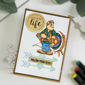 Handmade archer card 2 A slightly angled top-down view of the handmade masculine card, highlighting the card’s layout and design elements. The card includes a central digital stamp of an archer, layered with a background of die-cut arrows and a green watercolor paper. Text stickers are placed in the top-left and between the arrows