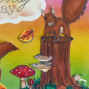 Close up picture of the coloureed squirrel on tree trunk "Close-up of squirrel on a tree stump on a handmade autumn card with ink blending. The detailed image shows a squirrel with warm fur tones sitting on a tree stump, framed by a softly blended autumn background in shades of pink, yellow and green distress ink to enhance the card’s autumnal feel.