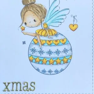 Close up picutur fairy bubble and sentiment xmas Close-up of the Fairy Bauble stamp, with the fairy resting in a hanging Christmas bauble alongside the sentiment ‘XMAS’ in die-cut letters. The soft shimmer effect highlights the fairy Christmas card's enchanting centrepiece