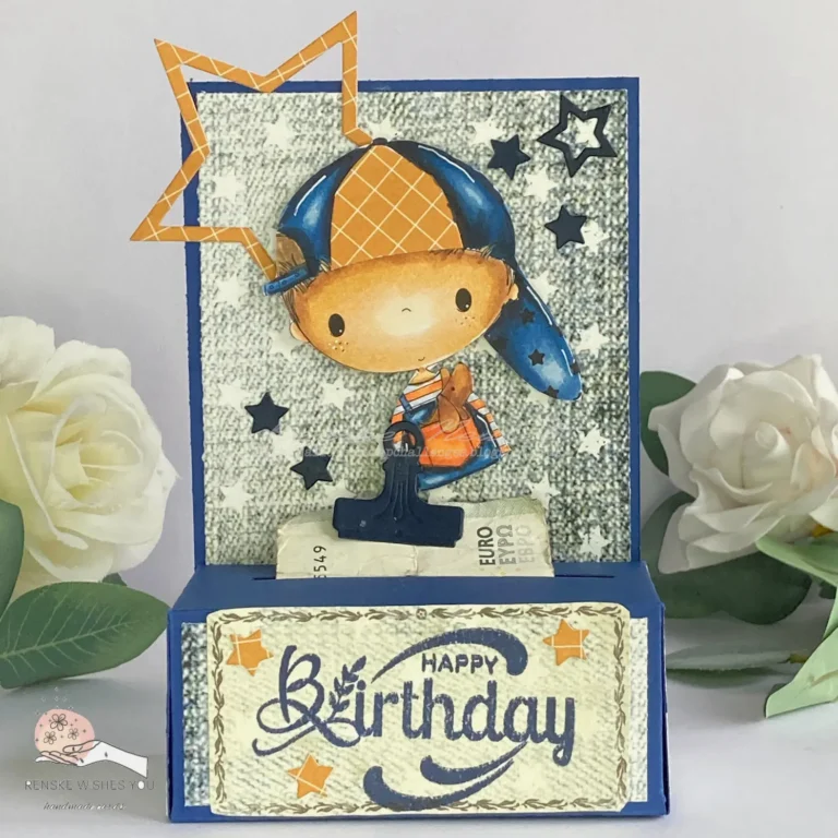 Front view of the completed DIY money roll box. The dark blue box is decorated with stars, the 'Little Dude' digital stamp, and a 'Happy Birthday' sentiment. The design is vibrant and personal.