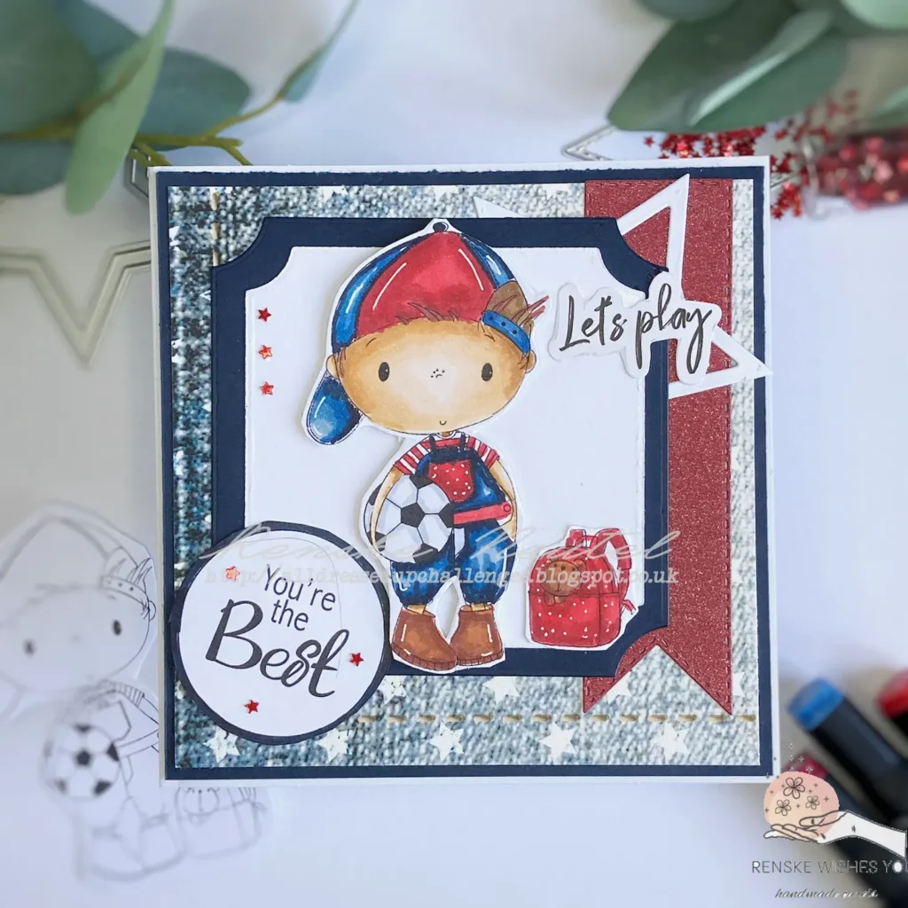 Flat lay view of the completed football-themed card featuring the 'Back to School Boy' digital stamp from All Dressed Up Stamps. The card showcases a layered design with a blue background, patterned paper with white stars, and sentiments 'Let’s Play' and 'You’re the Best' prominently displayed, creating a vibrant and playful look