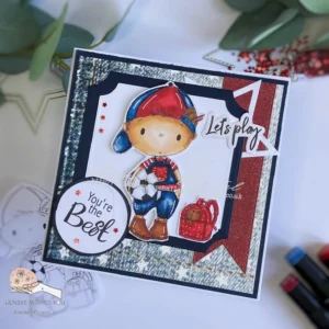 Football-themed card All Dressed up stamps (2) Angled flat lay view of the finished football-themed card, prominently featuring the 'Back to School Boy' digital stamp from All Dressed Up Stamps. The card highlights its vibrant colors and layered textures, including a red banner and decorative elements that enhance the overall football theme