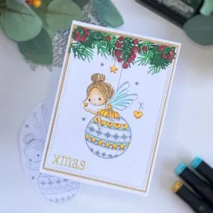 Handmade Fairy Christmas card with a bauble All Dressed Up STamps (2) Angled top-down view of the fairy Christmas card, highlighting the layers and dimension created with conifer branches, holly, and shimmering gold accents. The Fairy Bauble stamp stands out as the focal point, with a matte gold frame adding elegance to the festive scene.
