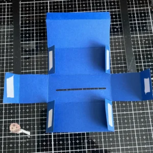 Money roll box with duoble sided tape Opened DIY money roll box showing the interior. The placement of the double-sided tape is visible, showing where to secure the flaps when assembling the box.