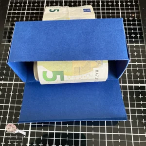 The roll of money in de box DIY money roll box with the bottom flap open, showing how the rolled-up money fits neatly inside. The box allows for a creative way to gift money.