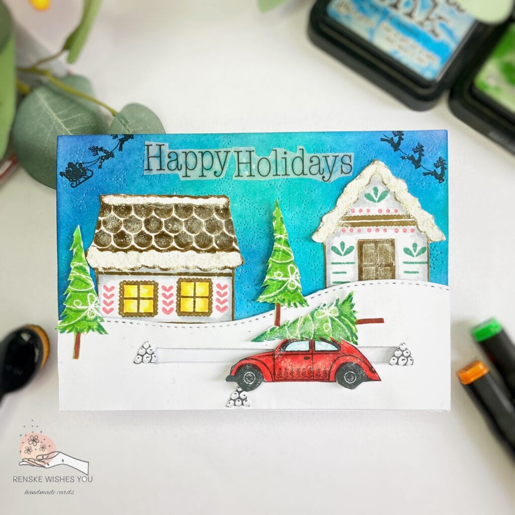 Top view of a flat Christmas slider card showing the full design, including a festive village scene with a moving car and a vellum 'Happy Holidays' sentiment.