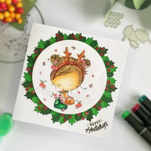 DIY Christmas card wreath with christmus hugs from All Dressed Up Stamps (2) An angled view of the DIY Christmas card wreath with the Christmas Hugs digital stamp from All Dressed Up Stamps. The card features a girl embracing a deer, surrounded by a festive wreath of holly and berries. The sentiment 'Happy Holiday' is visible in the bottom-right corner, while the wreath creates a stunning focal point around the illustration.