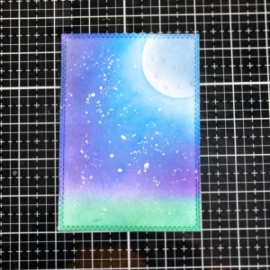 A completed background for the Mice Christmas card, featuring a soft, glowing moon surrounded by a deep blue and purple night sky. The ink blending creates a smooth gradient effect, and the moon stands out brightly in the centre. The scene is now ready for the final touches of the card design.