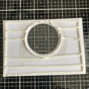 Back view of the patterned paper on the Christmas shaker card, showing the foam tape fully applied along the edges and center. This setup provides depth for the shaker elements while securely attaching the paper to the card base, giving the card a raised, interactive design.