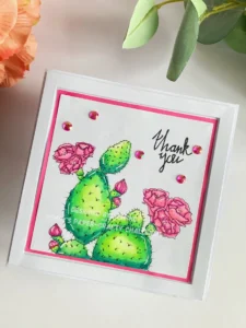 Cactus Thank you card Alex Syberia Desings Angled top-down view of the handmade cactus thank you card. The card design includes a cactus illustration with a pink border, a white die-cut frame, and subtle embellishments for added texture.