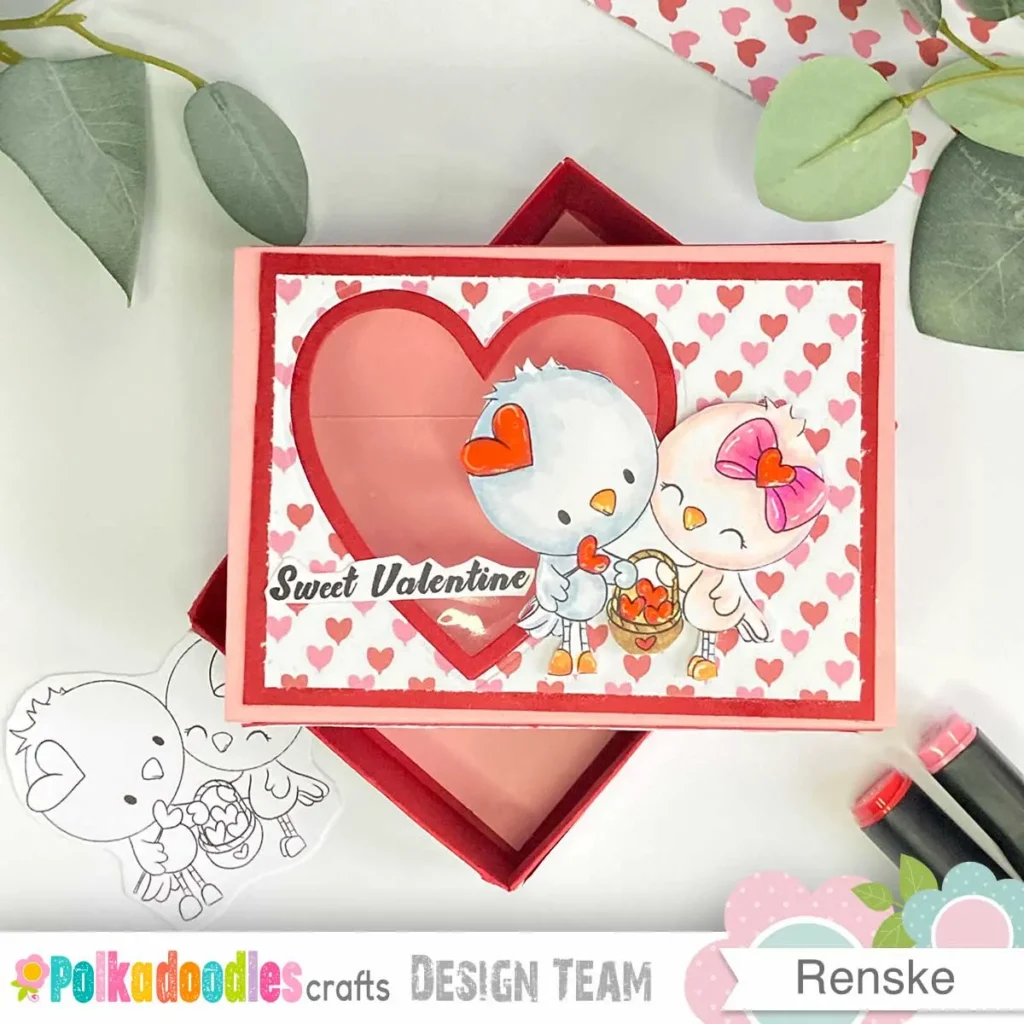 top-down view of the valentine treat box, with the red inner box at the bottom and the pink sleeve placed diagonally on top, showcasing the layered design.