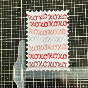 Xoxo background using the T ruler A step-by-step shot of creating the xoxo card background for the DIY Valentine card design, using a T-ruler to align the die-cut elements precisely.