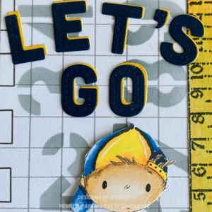 Close up of the text le';s go Detailed close-up of the sentiment “Let’s Go” on the back to school card idea. The die-cut letters in blue and yellow are layered for contrast and dimension.