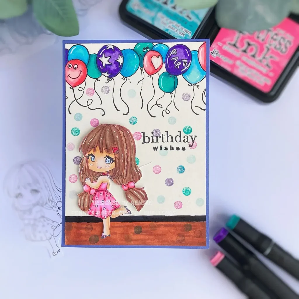 Top-down view of the handmade birthday card showing a layered design with a coloured girl image, balloon background, and stamped sentiment. A clean, festive layout with soft colours.