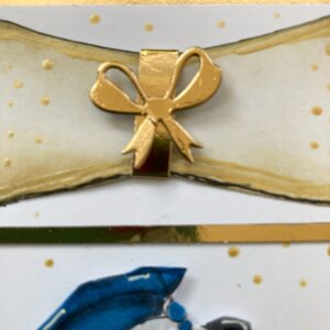 Bow on diploma scroll Detail shot of the gold bow on the DIY diploma scroll, featuring hand-cut shimmer paper, wrapped gold strip, and dimensional adhesive for a raised look.