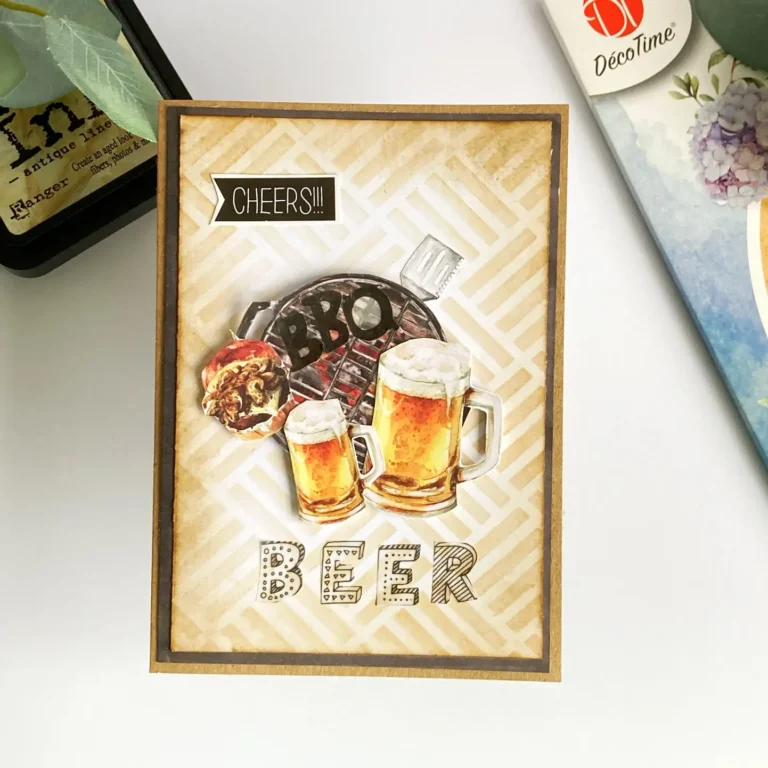 Overhead view of a handmade DIY masculine birthday card featuring a beer and BBQ theme. The card is built on kraft cardstock with layered die cuts of a barbecue, beer glasses, hamburger, and spatula. The background has a rustic brown distress ink design using a stencil pattern. A vellum sentiment spelling 'BEER' sits below the focal image, with a small 'cheers' sticker in the top corner.