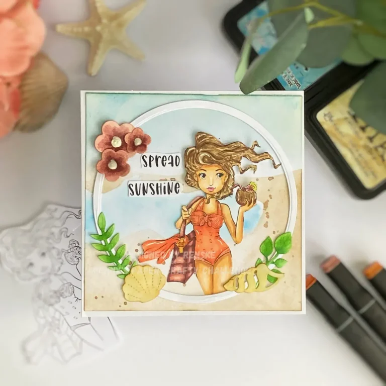 Flat-lay photo of the full handmade boho beach card, taken from above. The card features a soft beach scene with sandy tones, blue sky, and a framed digital stamp of a girl holding a coconut. Decorative elements like flowers, shells, and a sentiment reading “Spread Sunshine” are arranged around the focal point.