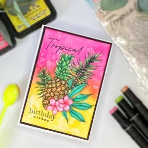 Angled Topical Birthday card (1) ngled top view of a handmade tropical birthday card with a vibrant background, pineapple image, tropical florals, and layered sentiment for added dimension