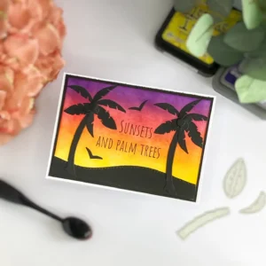 Handmade sunset card with silhouette die-cuts ropical sunset card with palm tree silhouettes, angled overhead view showing the smooth ink-blended sky in vibrant summer colours.