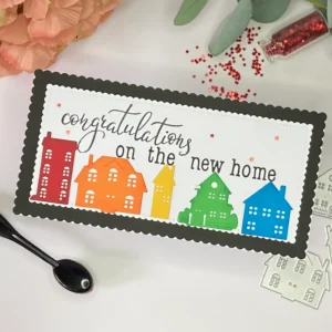New Home card rainbow houses ngled top view of the handmade slimline new home card, showing rainbow houses, sentiment, and layered background details.